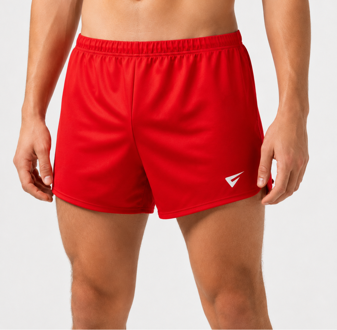 A close-up of a male model's lower torso wearing bright red athletic shorts with a white logo on the lower right leg, against a light gray studio background.