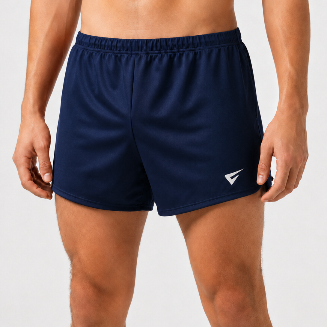 A close-up of a man's lower torso wearing navy blue athletic shorts with a white logo on the left leg, photographed against a light gray studio background.