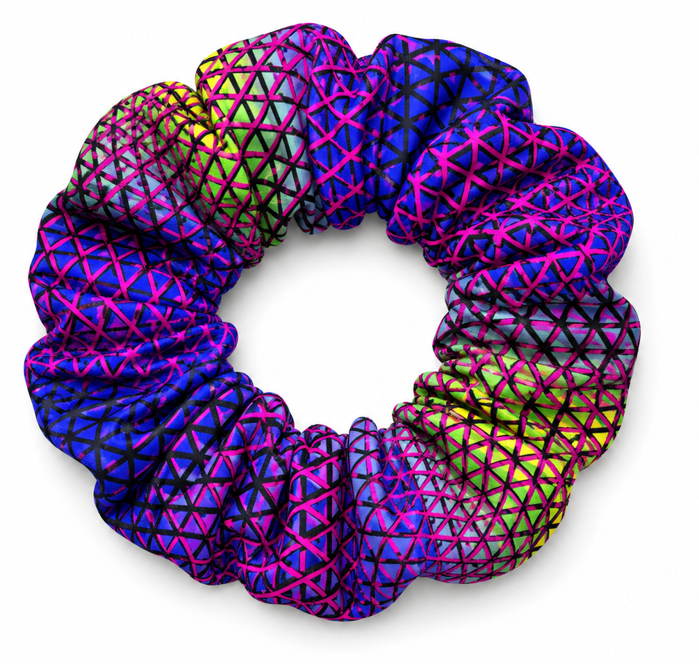 A single fabric scrunchie with a vibrant geometric pattern of interlocking triangles in neon pink, purple, blue, and lime green, shown on a clean white background.