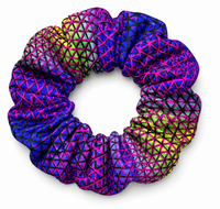 A single fabric scrunchie with a vibrant geometric pattern of interlocking triangles in neon pink, purple, blue, and lime green, shown on a clean white background.